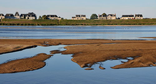 Reflection of buildings on beach against sky