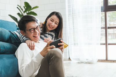 Young woman using phone while sitting on laptop