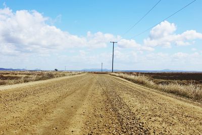 Road amidst field against sky