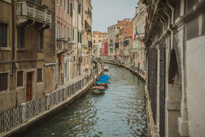 Rear view of woman on canal amidst buildings in city