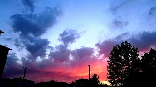 Low angle view of silhouette trees against cloudy sky