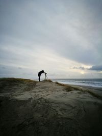 Man photographing against sky at beach