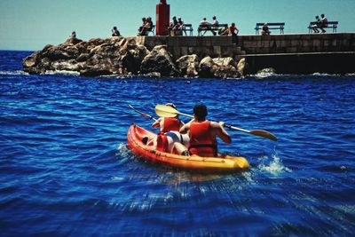 People in boat on sea against sky