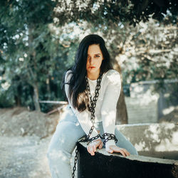 Portrait of young woman sitting on retaining wall