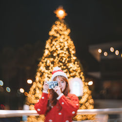 Rear view of woman with christmas tree at night