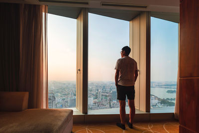 Rear view of man looking through window