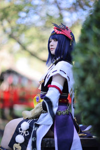 Portrait of young woman standing against trees