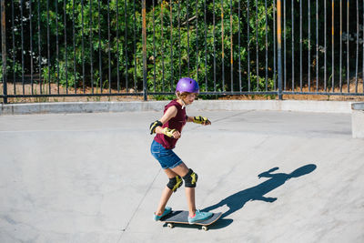 Teen girl in a purple helmet skateboards down a canyon at skate park