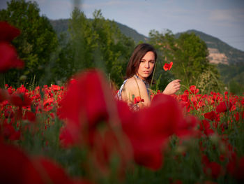 Portrait of young woman standing amidst flowers