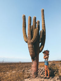 Person standing by cactus on field against clear sky
