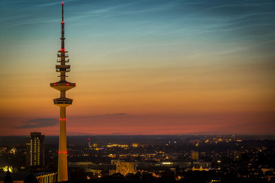 Illuminated buildings in city against sky during sunset