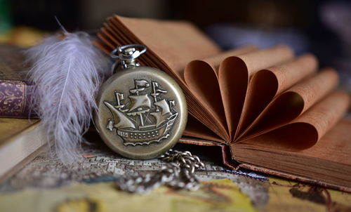 Close-up of pocket watch and book on the table