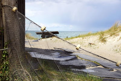 Fence on beach against sky