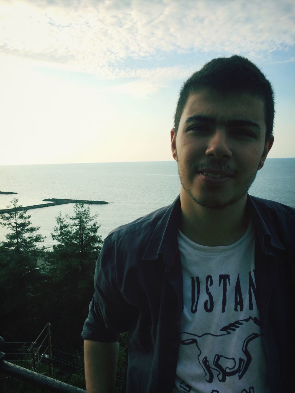 water, sea, sky, lifestyles, young men, waist up, person, young adult, leisure activity, standing, casual clothing, headshot, horizon over water, three quarter length, looking at camera, portrait, nature