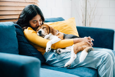 Portrait of young woman with dog on bed at home