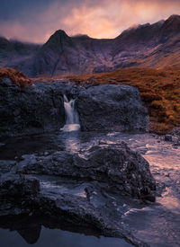 Scenic view of waterfall against sky during sunrise 