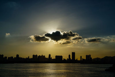 Silhouette buildings in city against sky at sunset