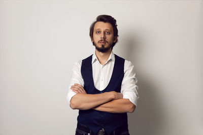 Serious portrait of a man in a vest in a white shirt on a white background in the studio