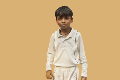 Portrait of boy standing against orange background