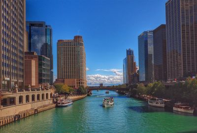 Modern buildings by canal against clear blue sky