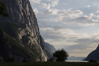 Evening shot of beautiful fjord valley, surrounded by mountains, cloudy blue skies.