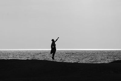 Rear view of woman walking at beach against clear sky