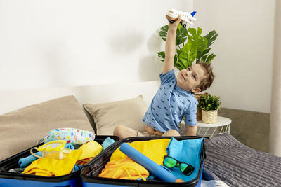 Little caucasian boy with blue shirt ready for vacation. happy child packs clothes