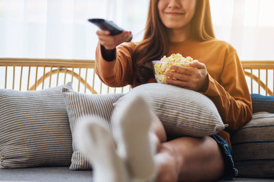 Young woman using mobile phone while sitting on sofa at home