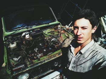 Portrait of young man standing by car