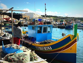 Fishing boats moored at harbor against sky