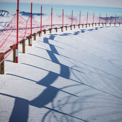 Shadow of railing on snow covered landscape