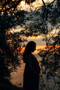 Silhouette woman standing against orange sky