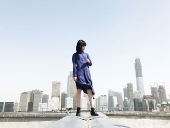 Woman standing on city skyline against clear sky