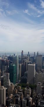 Aerial view of buildings in city against cloudy sky