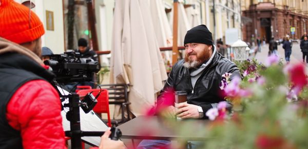 Smiling man with coffee sitting at sidewalk