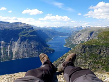 Low section of man on mountain against sky