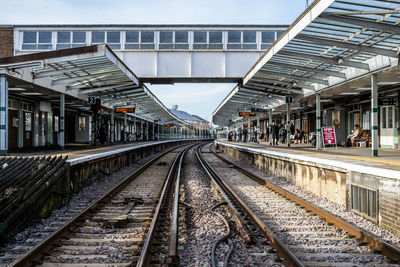 Passengers awaiting a train to arrive at a train station standing on the platform