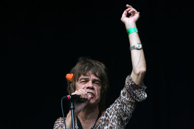 Portrait of mature woman with arms raised against black background