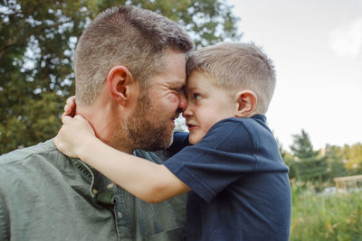 Close-up of playful father and son embracing while standing in forest