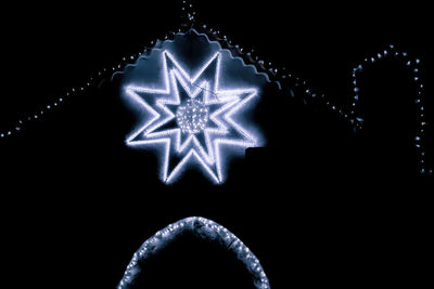 Close-up of illuminated christmas lights over black background