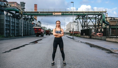 Confident woman with arms crossed standing on road