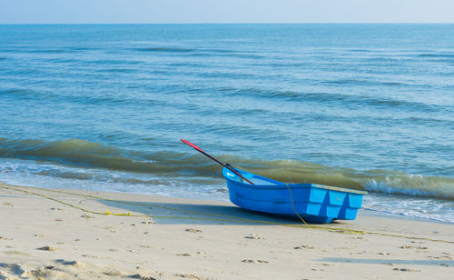 Boat moored on beach against sky