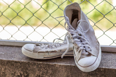 Close-up of shoes on chainlink fence