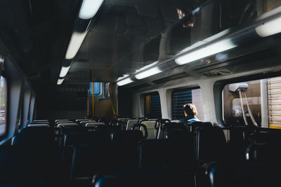 Rear view of woman sitting in empty train