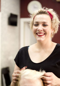 Cheerful female hairdresser styling customer hair in salon