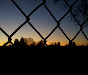 Silhouette fence against sky during sunset