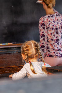 Rear view of teacher teaching female student in classroom