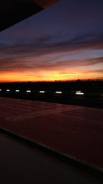 Airplane on runway against sky during sunset