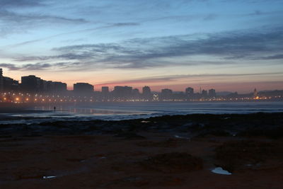 Sea and buildings against sky during sunset