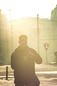 Full length portrait of young man standing on street in city
